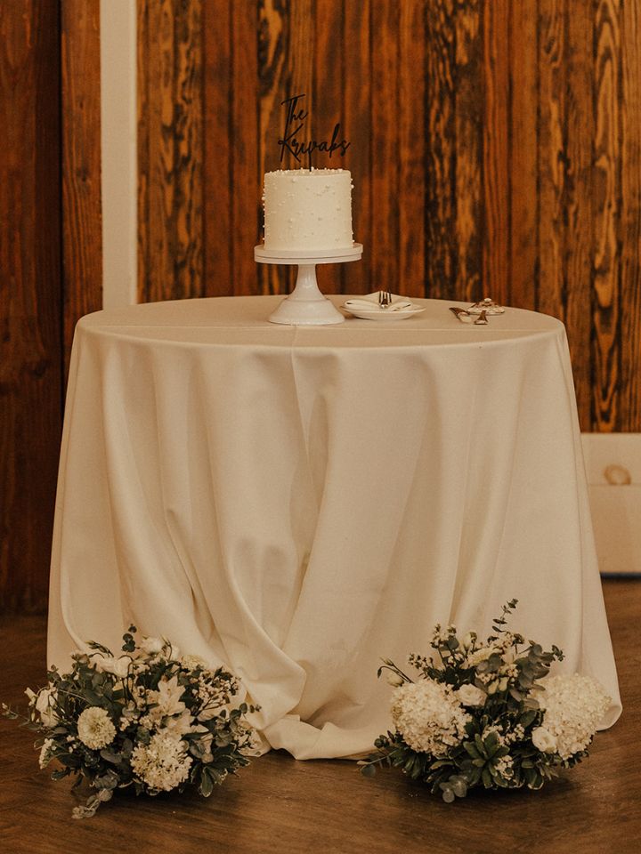Cake table with small flower arrangements at base.