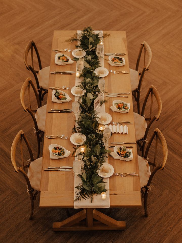 Rectangular guest table with greenery garland down the center.