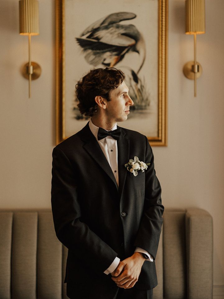 Groom in black tuxedo with white floral pocket square.