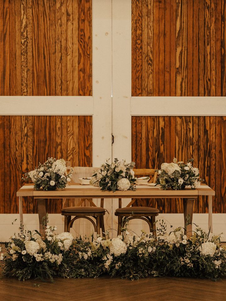 Sweetheart table with white and green flower arrangements.