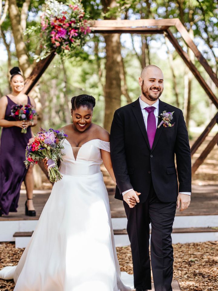 Bride and groom walk back down aisle after wedding ceremony.