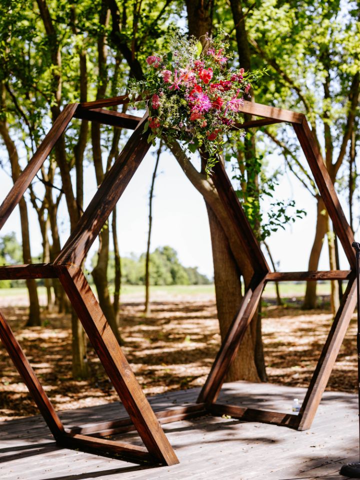 Hexagon arch with purple wedding flower arrangement on top corner.