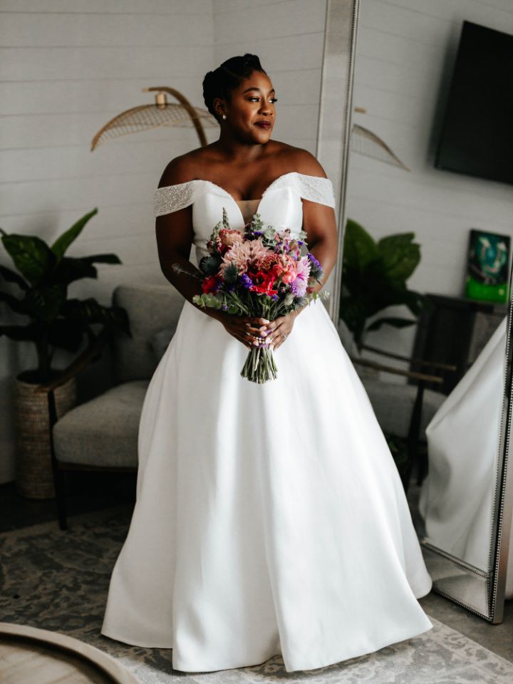 Bride smiles and holds her bridal bouquet.