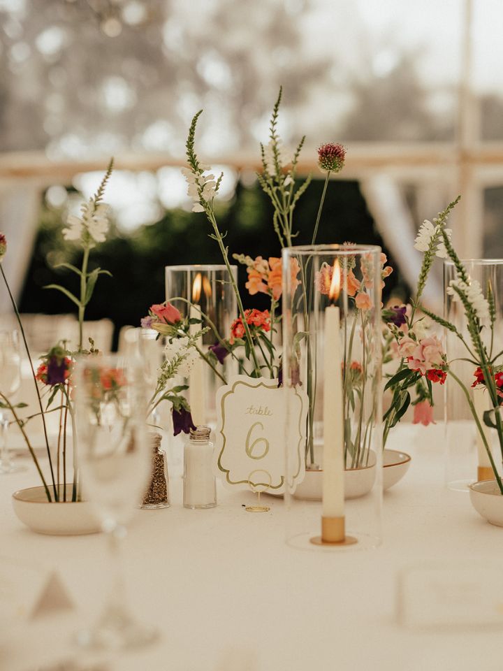 Floral frog arrangements at wedding reception guest tables.