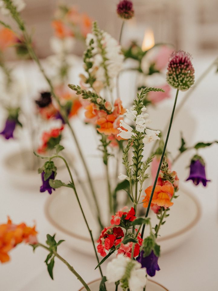 Summer garden wedding flowers in low dishes with floral frog pins for guest table centerpieces.