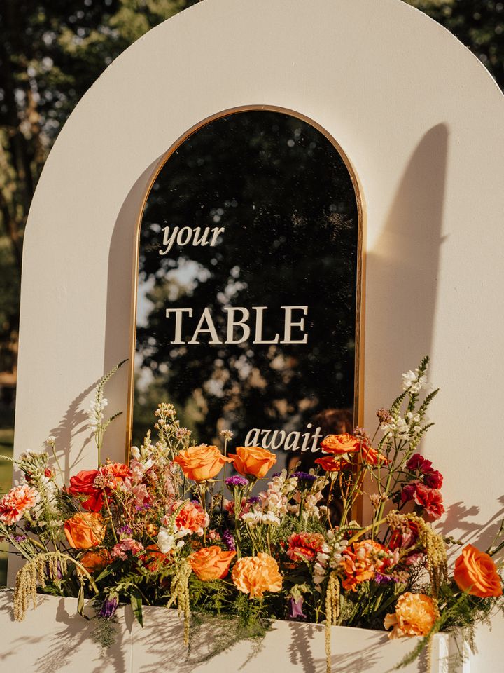 Closeup of flower arrangement in mirror signage for seating chart.
