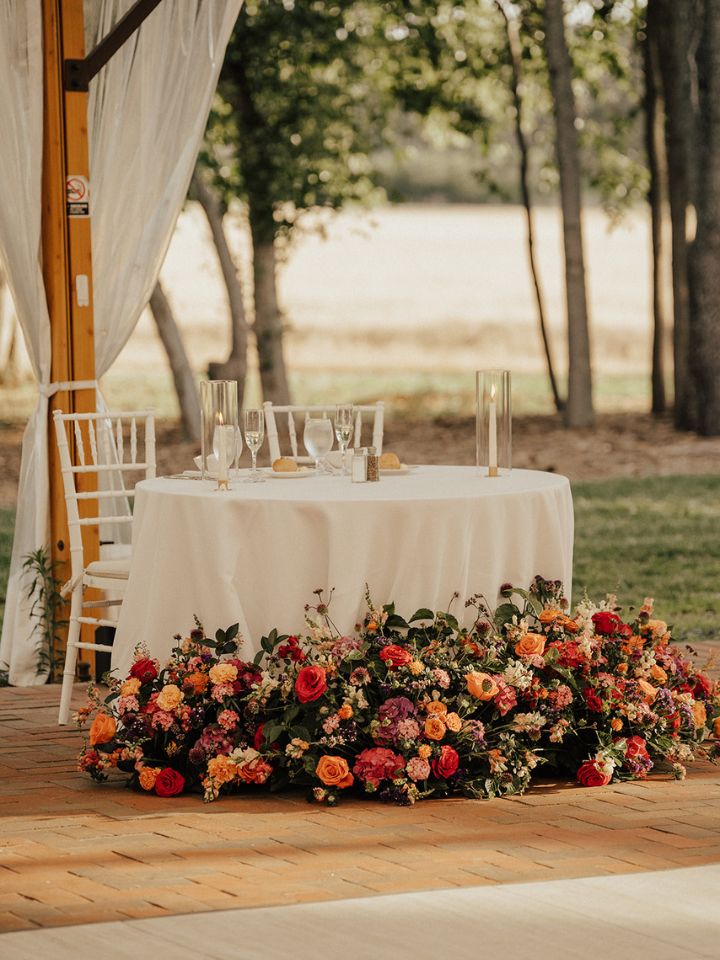 Large flower arrangements sit at base of sweetheart table.