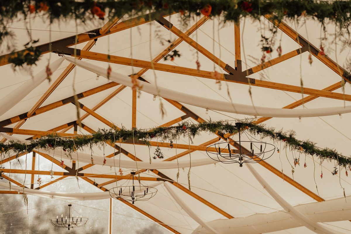 View of Pavilion tent ceiling at Kent Island Resort with greenery and florals on light strands.