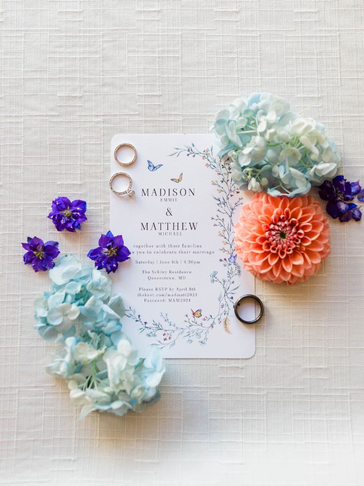 Flat lay photo with wedding invitation, flowers, and jewelry.