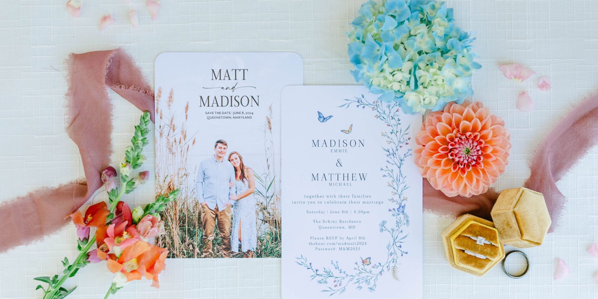Flat lay photo of wedding invitation suite, flowers, and ribbon.