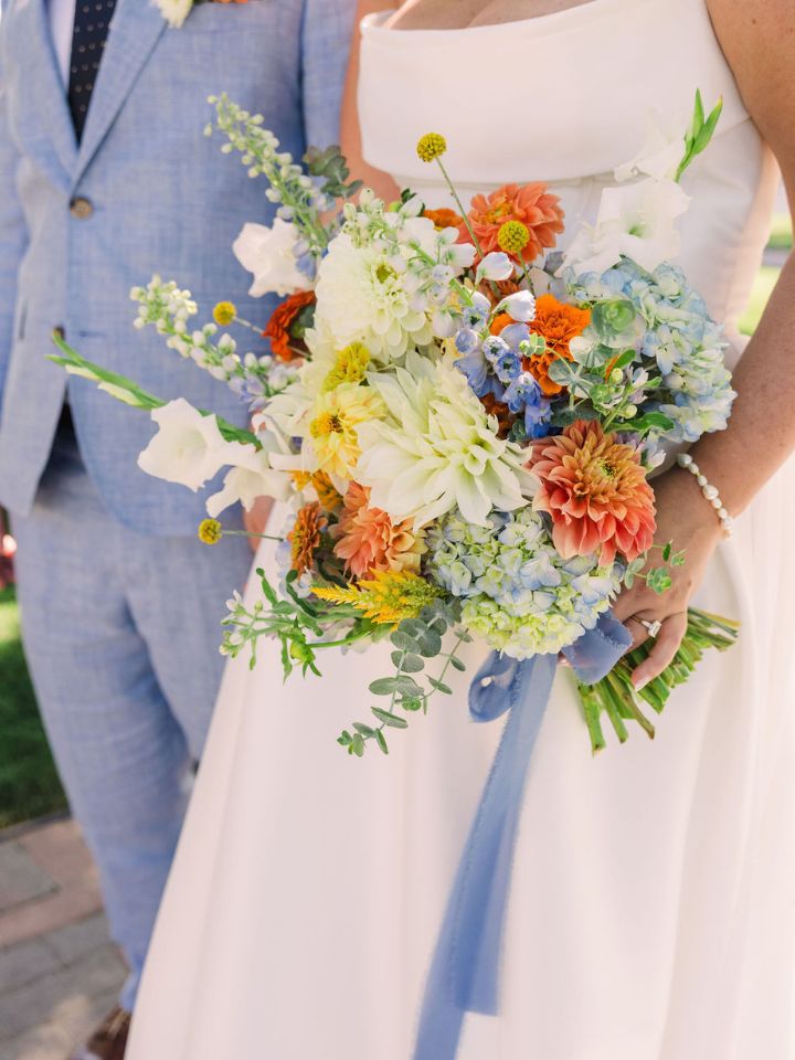 Closeup of bridal bouquet, with trailing light blue ribbon.