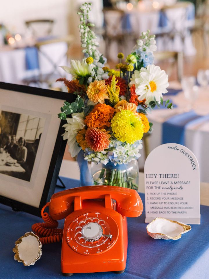 Guest book table with bright orange phone and flower vases.