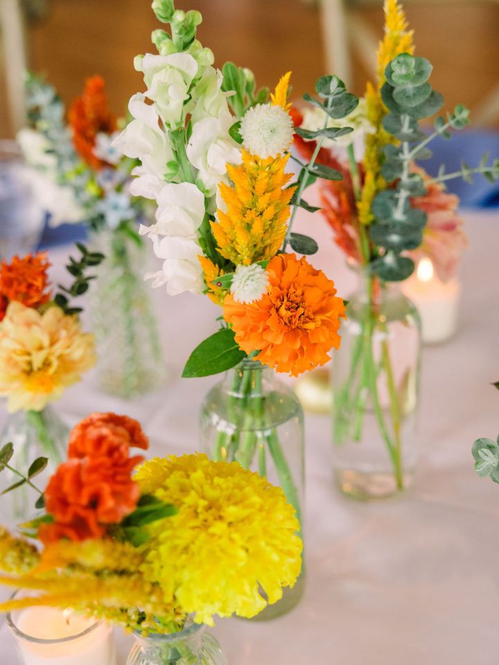 Bud vases on a guest table with white table cloth.