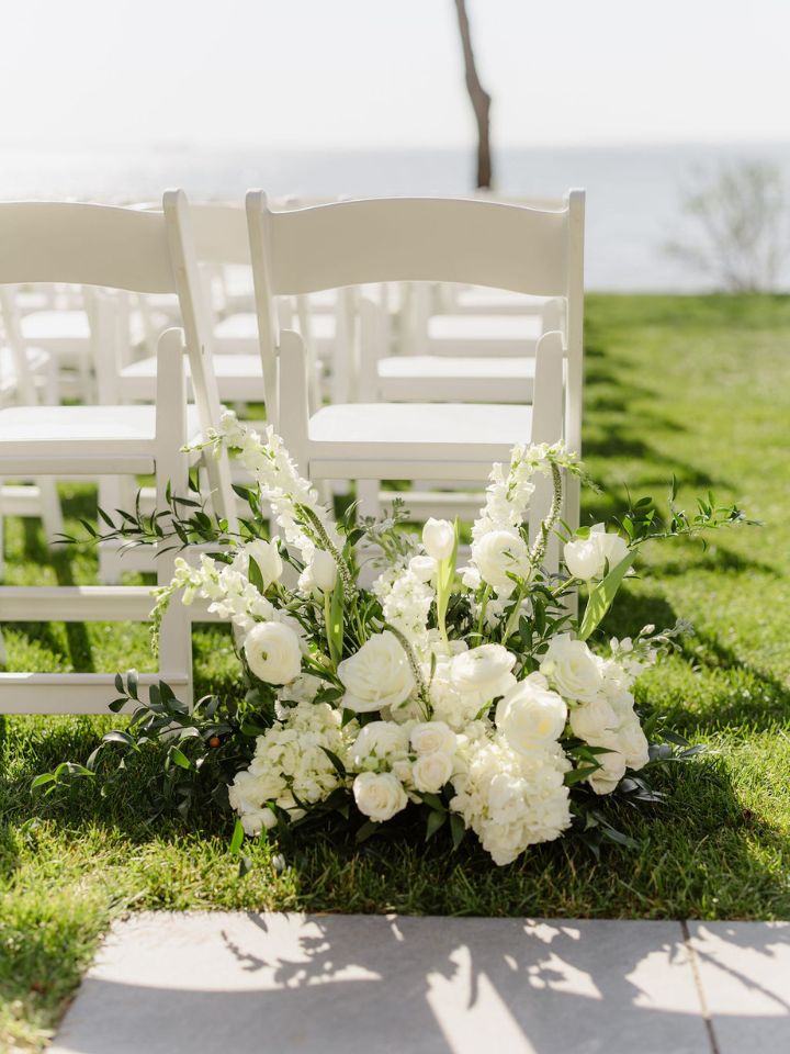 White flower arrangement at entrance to wedding ceremony aisle.