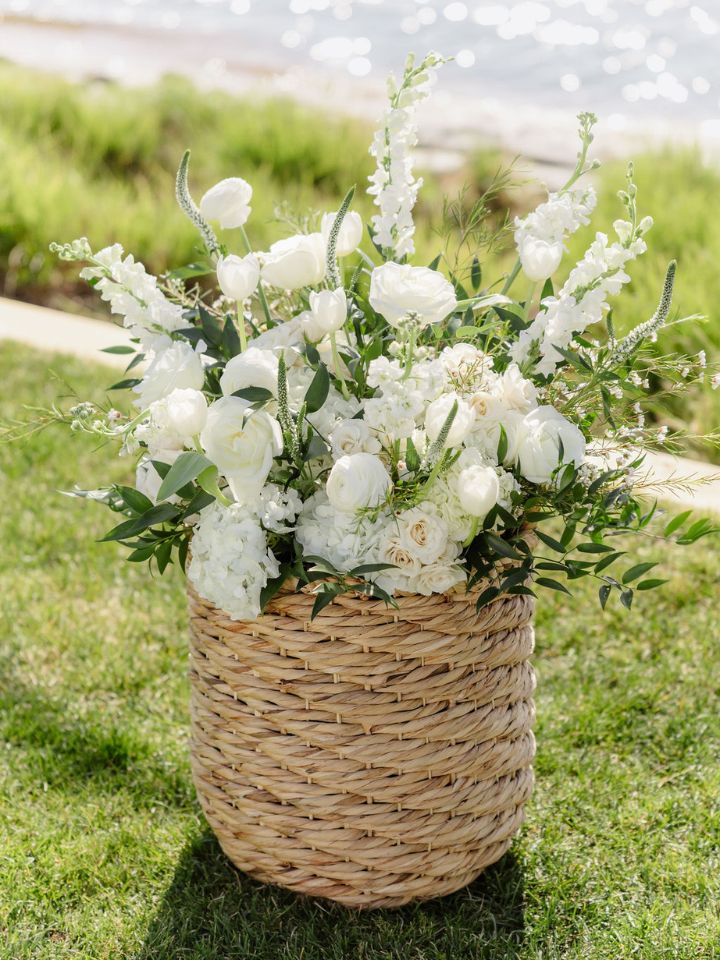 Rope/wicker basket with large white flower arrangement in it.