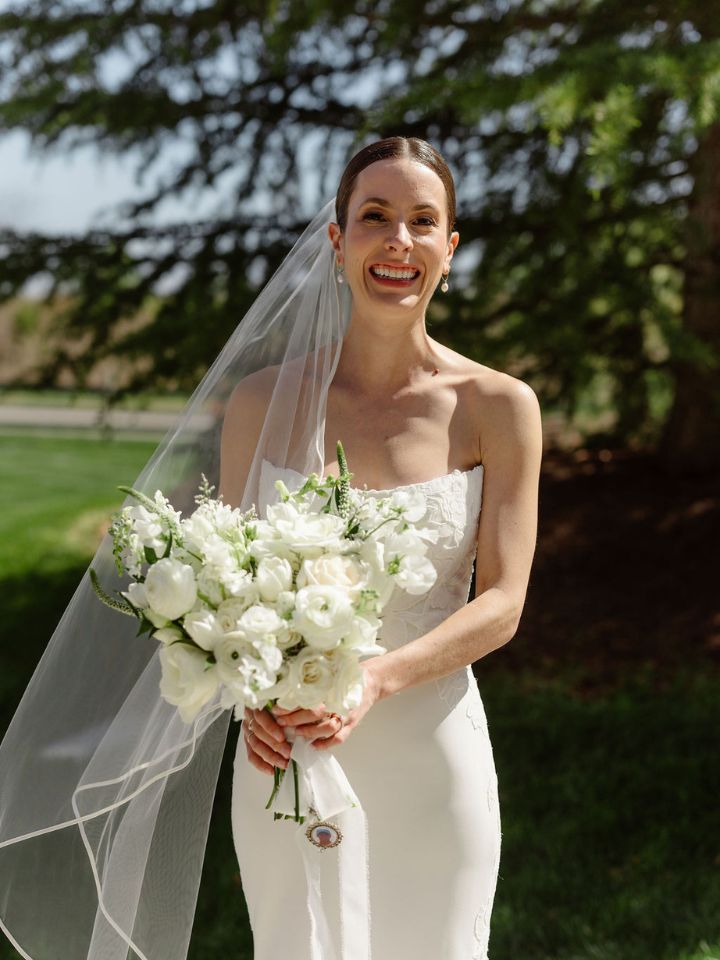Bride holds her white flower bridal bouquet towards camera.