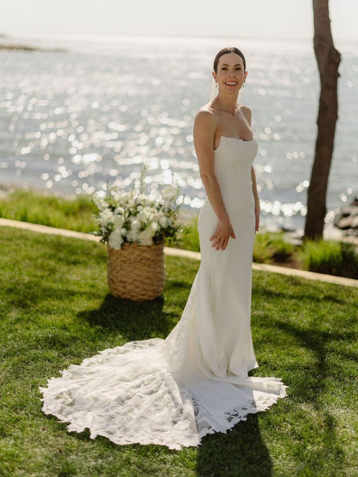 Bride poses next to basket flower arrangement for ceremony.