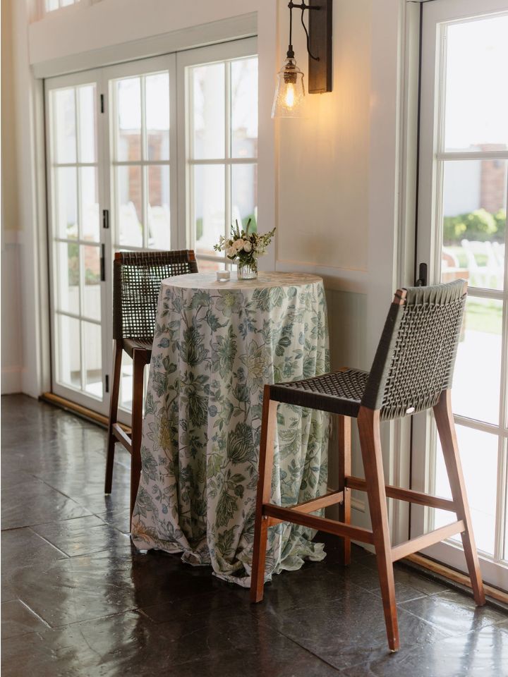 Tall table with stools and small flower vase for cocktail hour.