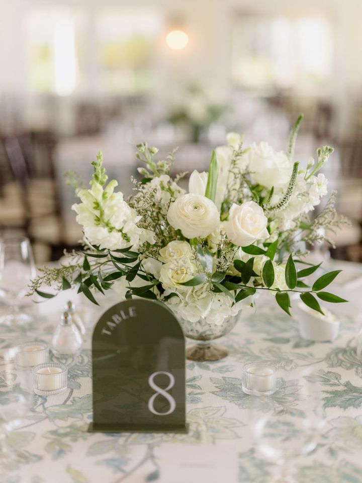Blue and white patterned tablecloth with white flower arrangement centerpiece.