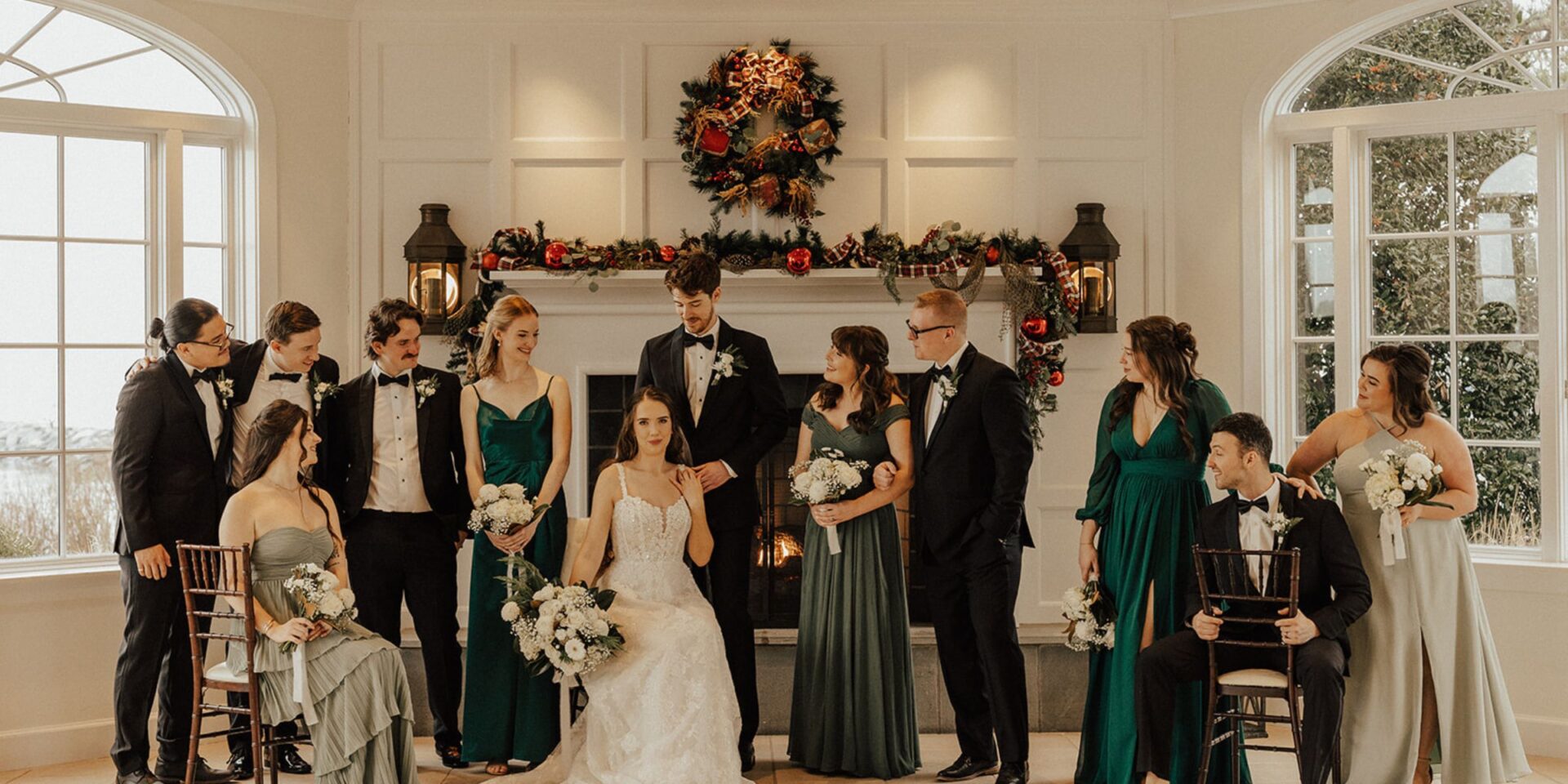 Wedding party poses in chairs and standing as a group.