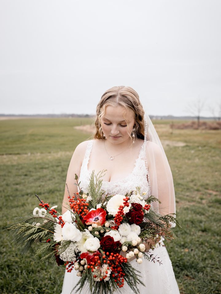 Bride looks down at her christmas bouquet.