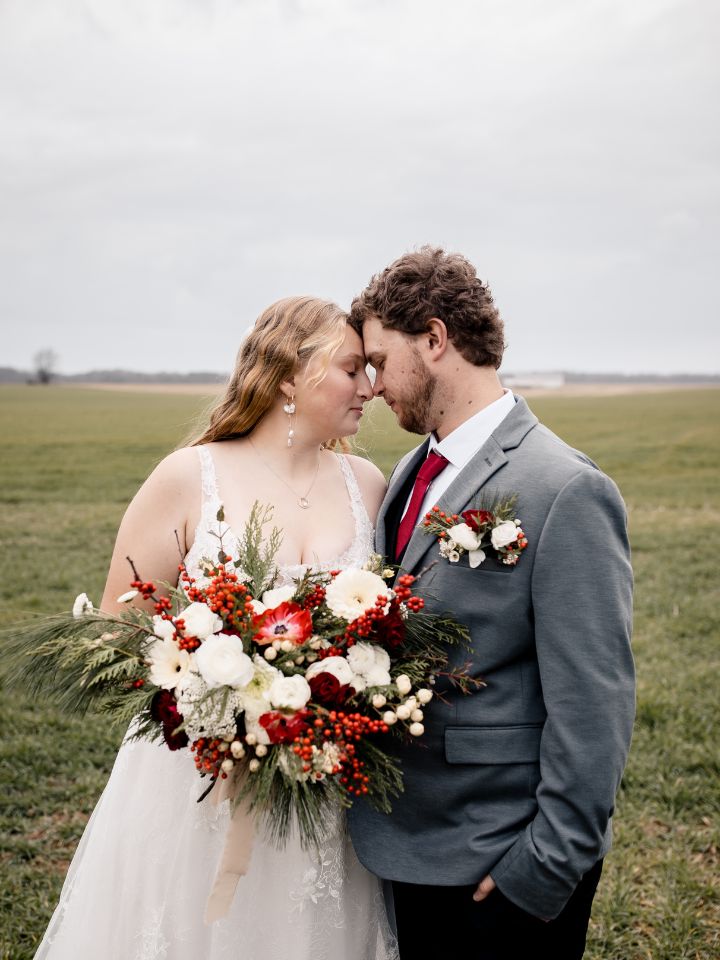 Bride and groom pose in field.