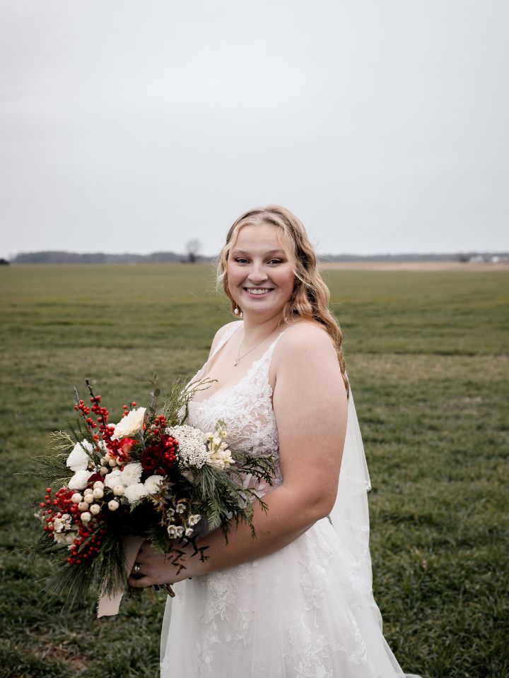 Bride holds her winter elopement bridal bouquet and smiles at camera.
