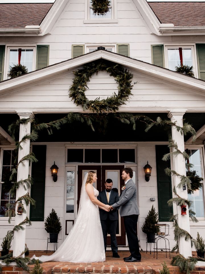 Bride and groom exchange vows on front porch of old home.