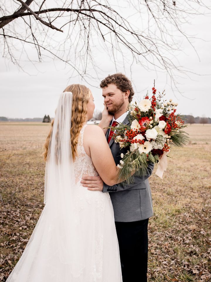 Bride and groom pose under tree.
