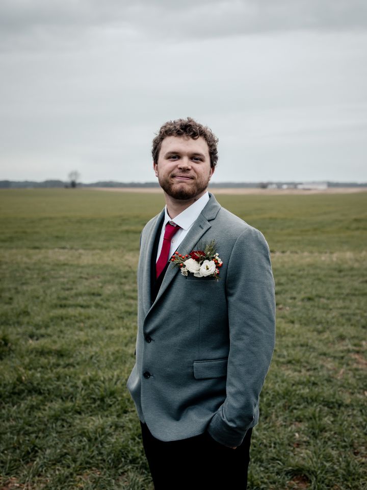 Groom in grey suit looks towards camera.
