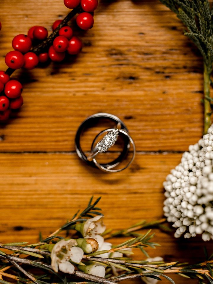 Wedding rings and winter flowers on a wooden table.