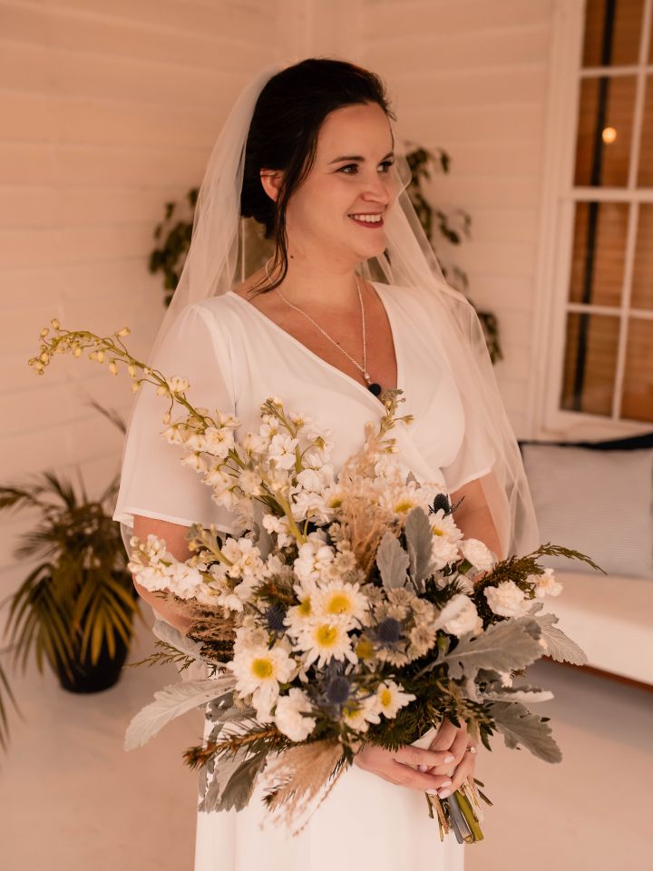 Bride holds wintry bridal bouquet.