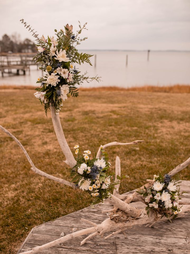 Driftwood wedding ceremony arch with flower arrangements.