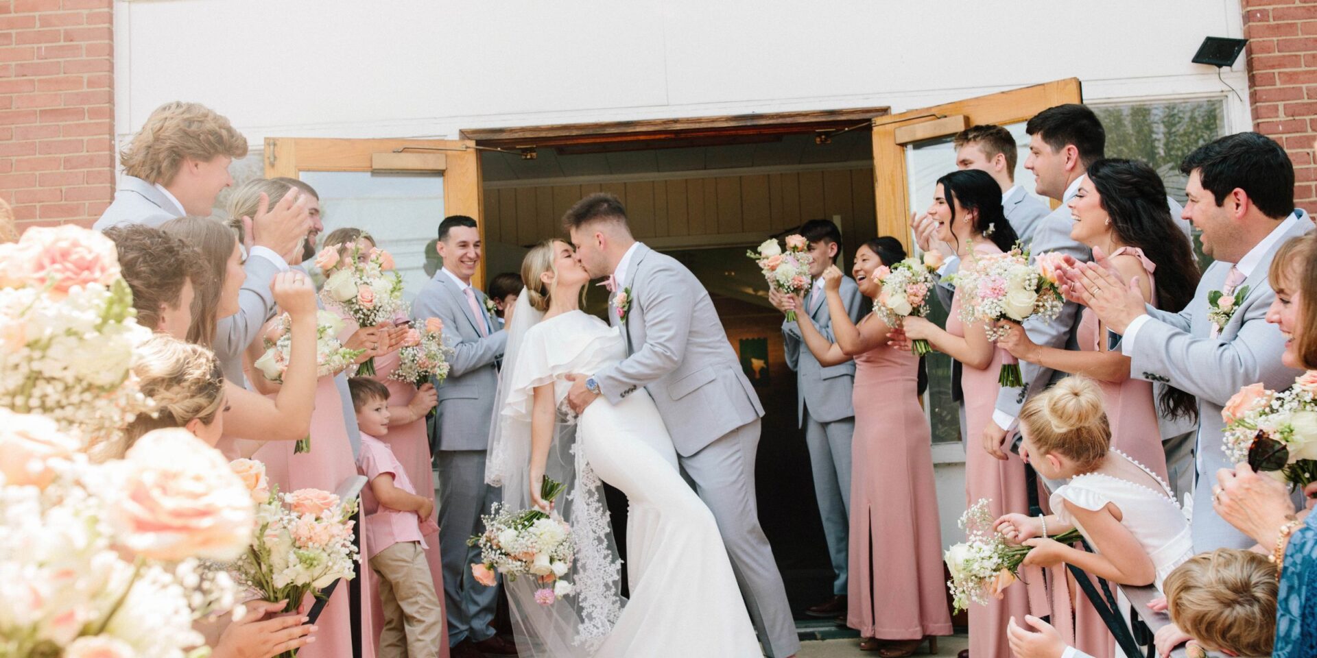 Bride and groom dip kiss as they leave the church ceremony.