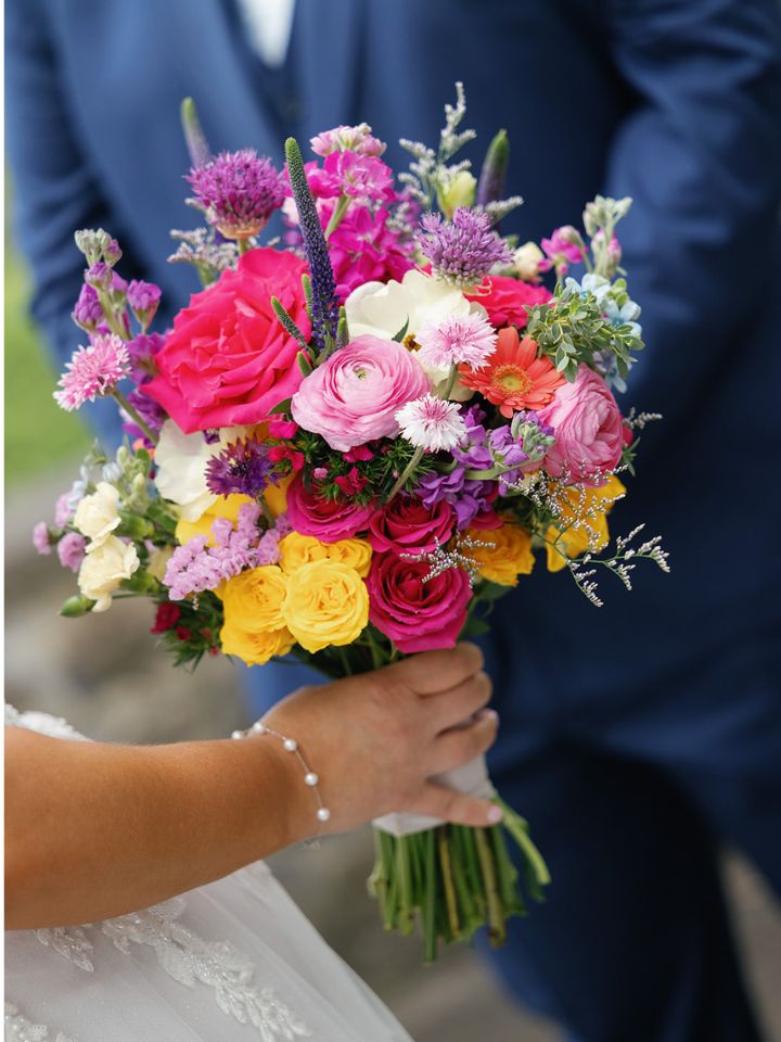 Closeup of bridal bouquet in hot pink, yellow, and purple.