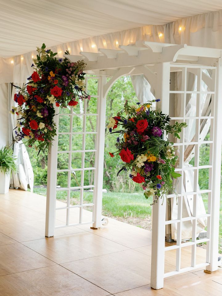 White pergola for wedding ceremony with colorful flowers.