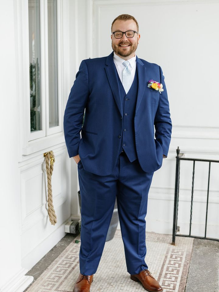 Groom in dark blue suit with fresh flower colorful pocket square style boutonniere.