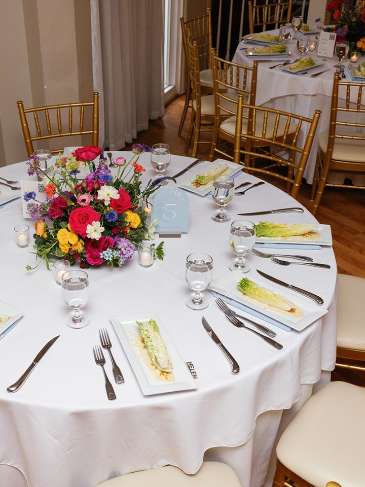 Round guest tables with white linens and bright flower arrangements.