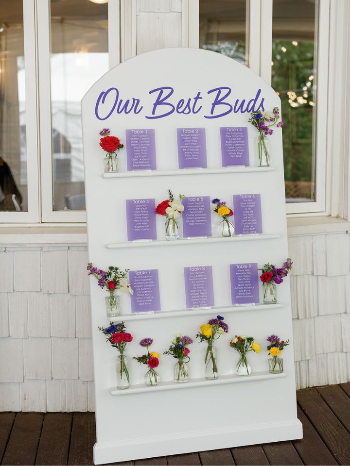 Seating chart signage with small shelves to hold colorful flower bud vases.