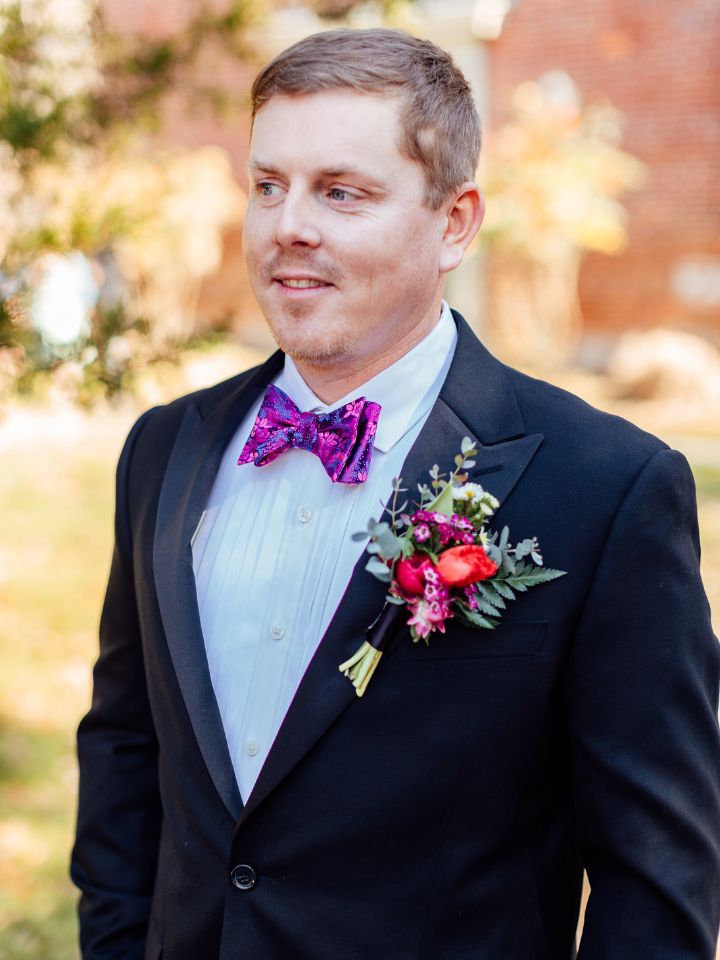 Groom in black tux with a colorful flower boutonniere.