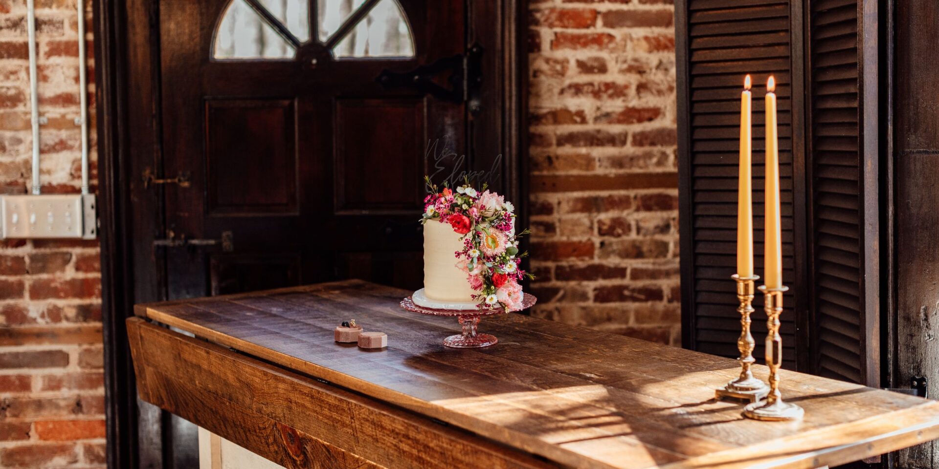 Wedding cake sits on table inside old brick chapel.