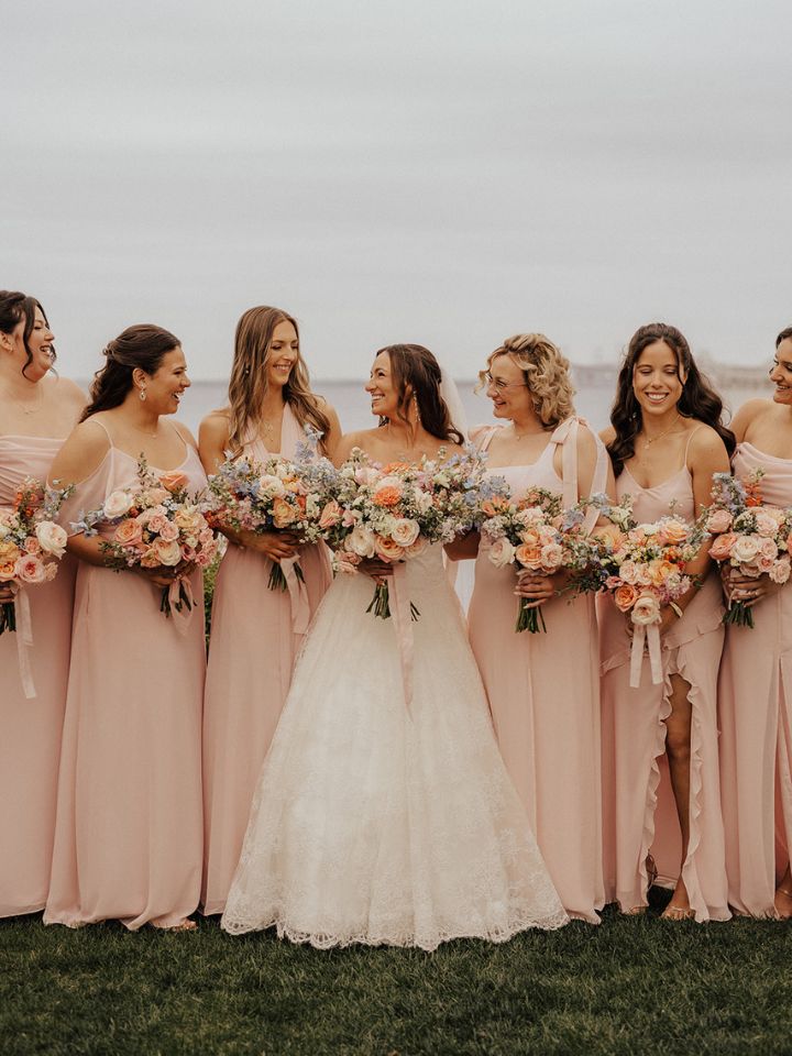 Bride and bridesmaids in soft pink dresses hold their spring bouquets.
