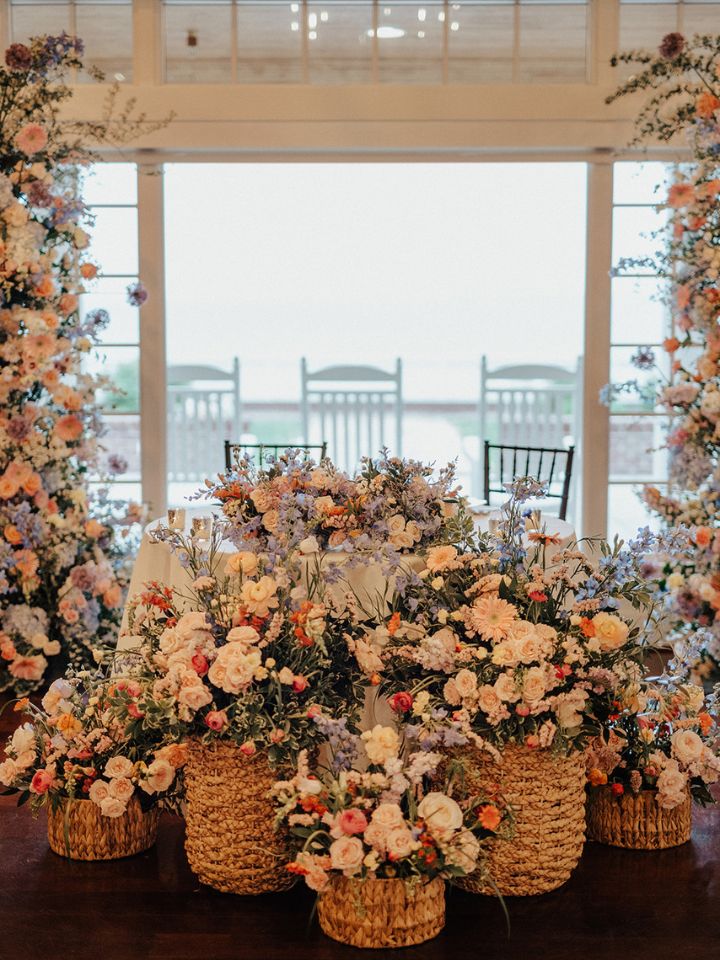 Sweetheart table with large flower basket arrangements in front.
