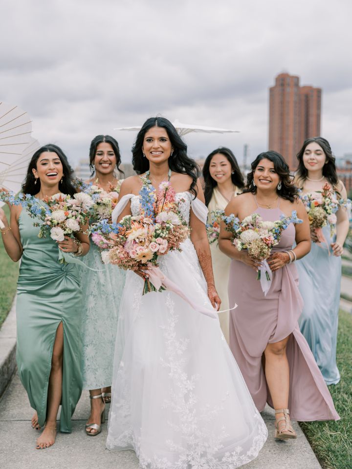 Bride and bridesmaids in pastel dresses carry bouquets at Federal Hill for a Baltimore Wedding.