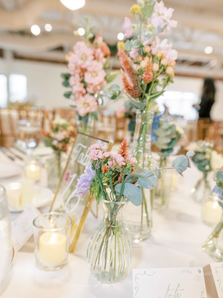 Wedding reception table with bud vases and votive candles.