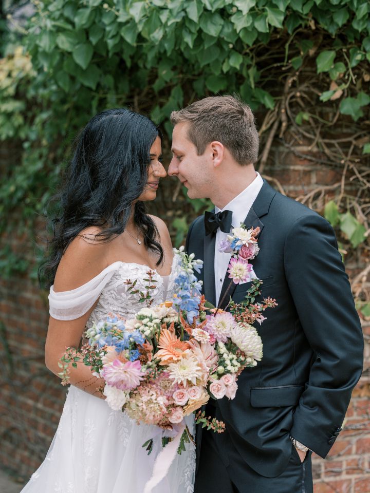 Bride and groom pose near brick wall.